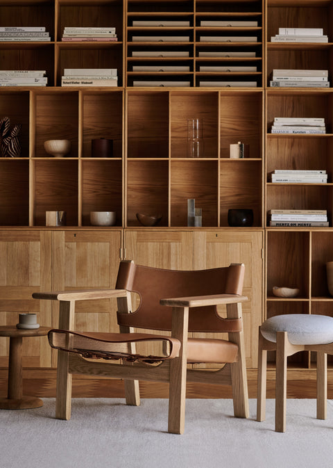 Pioneer Stool by Fredericia with light grey seat next to Borge Mogensen Spanish Chair and oak bookcase
