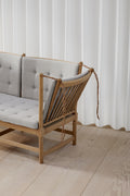 Lifestyle close up of Fredericia Spokeback Sofa in light grey fabric showing adjustable side and oak spindles
