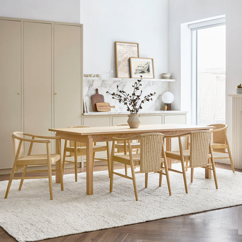Gus* Modern Strand Dining Chair in Royal Oak with upholstered fabric at round dining table with white shelving and cork pendant lights