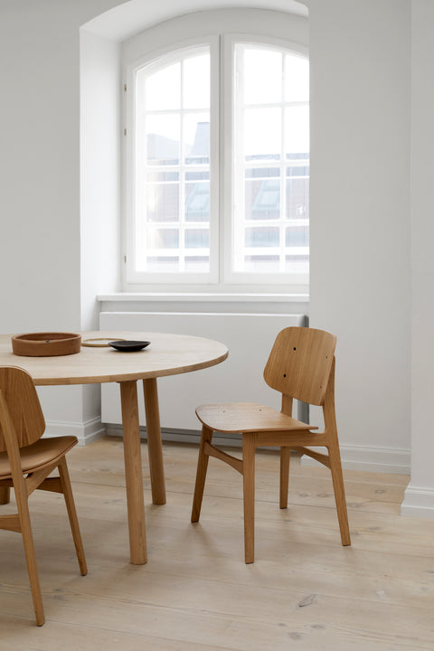 Taro round oak table paired with molded plywood dining chairs in a bright Nordic interior