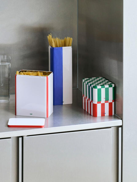 HAY Tin Container, Large, Off-White and Red, lidded tinplate storage tin, open with pasta beside a slim blue tin of spaghetti in a kitchen