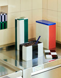 HAY Tin Container, Medium, Black and Off-White, lidded tinplate storage tin, open with coffee beans on a steel counter in a yellow tiled kitchen
