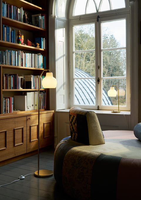 VL Ring Crown floor and table lamps by Louis Poulsen beside an arched window, brass and opal glass for warm Scandinavian lighting in Canada