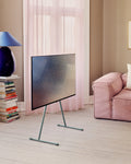 Pedestal Viva TV Stand in Charcoal, steel TV floor stand, holding a screen in a living room with a pink sofa and curtains