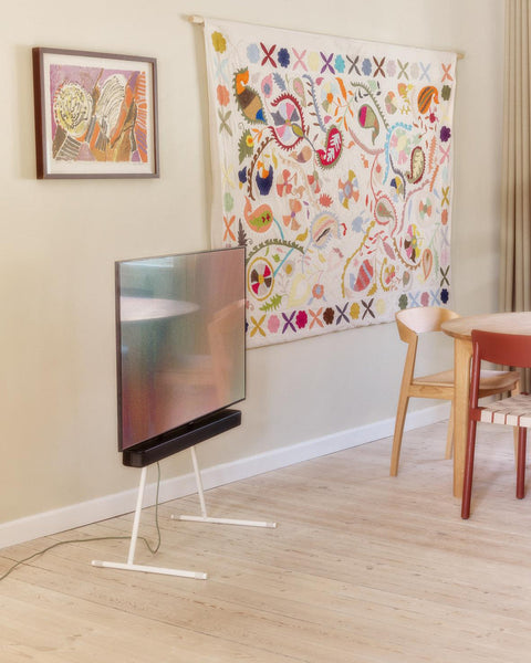Pedestal Viva TV Stand in Pearl, steel TV floor stand, holding a screen in a child's room with patterned wallpaper