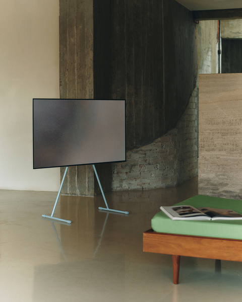 Pedestal Viva TV Stand in Powder Blue, steel TV floor stand, holding a screen in a room beside a wooden bench