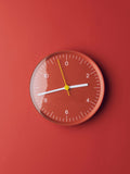 HAY Wall Clock, Red, recycled ABS wall clock, red dial and white hands, mounted flat against a deep terracotta red wall