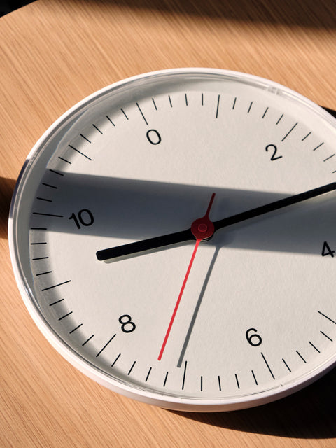 HAY Wall Clock, White, recycled ABS wall clock, angled close up of the white face and red second hand over an oak surface