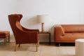 Side profile of Mogensen Wing Chair next to leather sofa, cognac leather and oak legs, modern Scandinavian furniture for Canadian homes