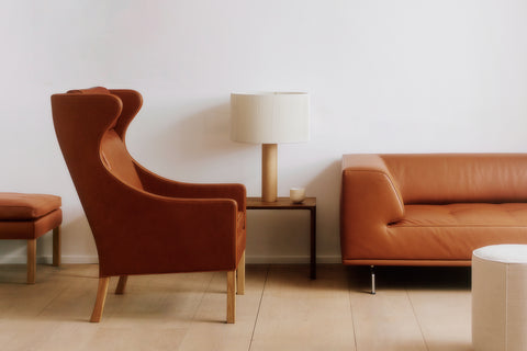 Side profile of Mogensen Wing Chair next to leather sofa, cognac leather and oak legs, modern Scandinavian furniture for Canadian homes