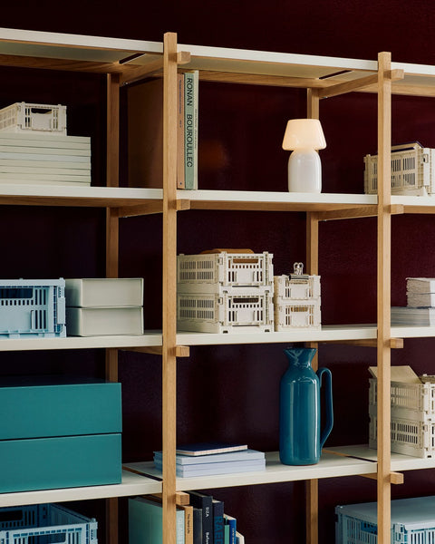 HAY Colour Crate, Medium, Off-White, recycled plastic storage crates, on wooden shelves with teal boxes, books and a jug, dark red wall