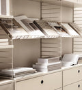 Beige String® System floor panels with shelving, showing books and storage styled in a modular setup.