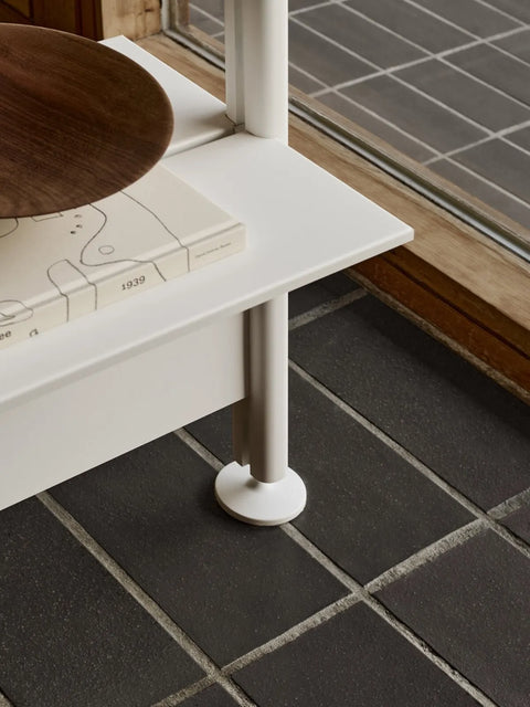 String Furniture Pira Leg in white with rubber pad on a tiled floor, adjustable shelving foot detail