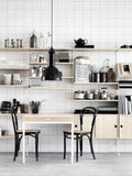 String Furniture shelving system in light wood with kitchen storage, dining table, and black chairs
