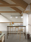 Muuto Rime Rail Lamp in black with three glass globes over minimalist Scandinavian high table and bar stools