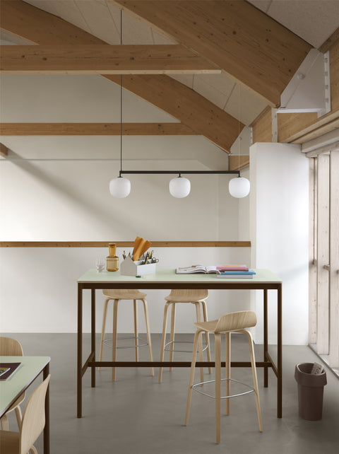 Muuto Rime Rail Lamp in black with three glass globes over minimalist Scandinavian high table and bar stools