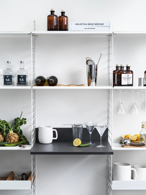 Scandinavian kitchen setup with String® System including shelves, bar accessories, and hanger rack