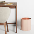 Blu Dot Binwell Wastebasket in Blush with terracotta swing-top lid styled next to a walnut desk