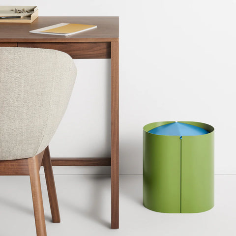 Blu Dot Binwell Wastebasket in Grasshopper green with blue swing-top lid styled next to a walnut desk
