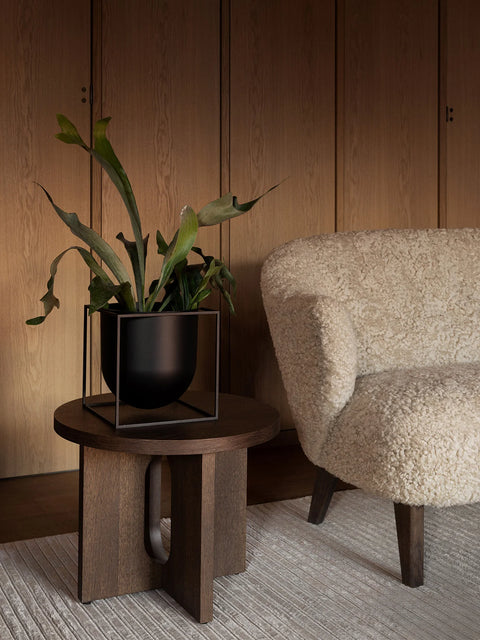 metal flower pot on a wood end table by audo copenhagen