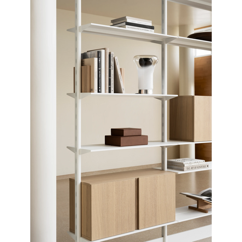 String Furniture Pira shelving in white with white oak cabinets, modular shelving styled with books