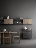Scandinavian dining and living space featuring oak String® System cabinets with flip doors and black frame shelving