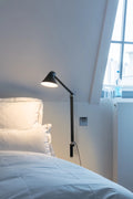 njp long arm wall lamp in black in a bedroom above nightstand by louis poulsen