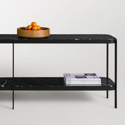 Blu Dot Comehither Long and Low Console Table in black Marquina marble and matte black steel, styled with a wood bowl of oranges on top and stacked Aperture magazines on lower shelf