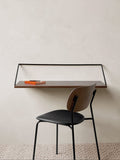 Audo Copenhagen Co Dining Chair, Without Arms, Partially Upholstered, Co Dining Chair with a black upholstered seat and dark wood back, set at a wall-mounted desk in a minimalist room