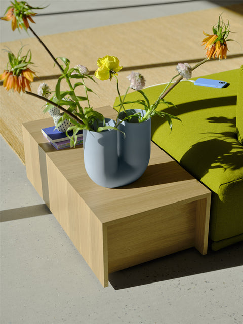 Connect Modular Sofa Table styled with flowers – natural oak veneer surface beside green sofa