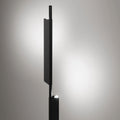Blu Dot Cowl Floor Lamp in black shown illuminated, sculptural pivoting shade casting warm LED light against a soft grey background