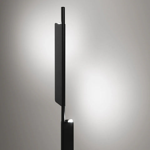 Blu Dot Cowl Floor Lamp in black shown illuminated, sculptural pivoting shade casting warm LED light against a soft grey background