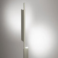 Blu Dot Cowl Floor Lamp in putty finish shown illuminated, with integrated LED light emitting warm glow from the pivoting shade against a soft grey background