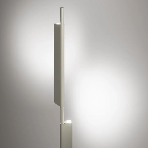 Blu Dot Cowl Floor Lamp in putty finish shown illuminated, with integrated LED light emitting warm glow from the pivoting shade against a soft grey background