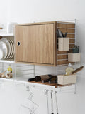 Beige String™ organizers mounted on modular shelving in kitchen with cabinet and storage accessories
