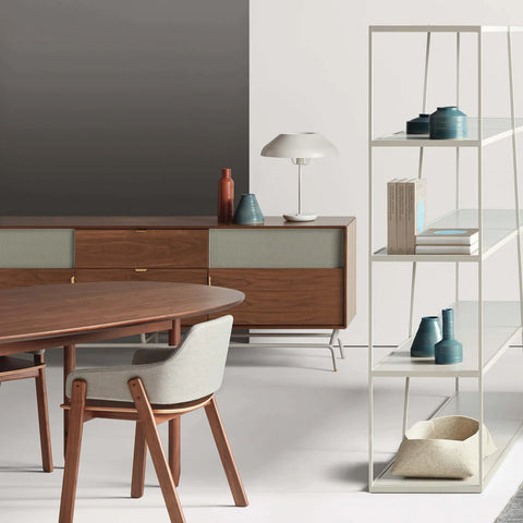 Blu Dot Dang 2 Door / 2 Drawer Console in walnut veneer with perforated steel door fronts, styled in a modern dining room with a walnut oval dining table, upholstered dining chair, white table lamp, and tall white shelving unit