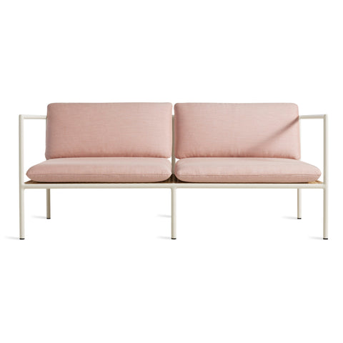 Blu Dot Dog Days Outdoor 2 Seat Sofa in Sunbrella Blush pink cushions with white powder-coated aluminum frame and all-weather rattan