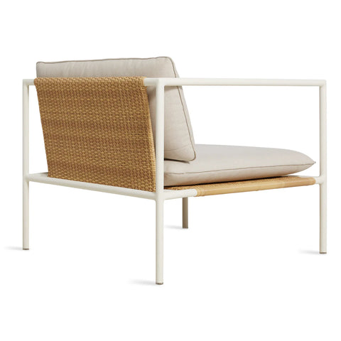 Blu Dot Dog Days Outdoor Lounge Chair in Sunbrella Linen cushions with white powder-coated aluminum frame and all-weather rattan, shown from the back angle to display the woven rattan panel