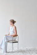 A woman seated on a DK3 Baia Chair in Balmoral White 02 with an oak back and chrome frame