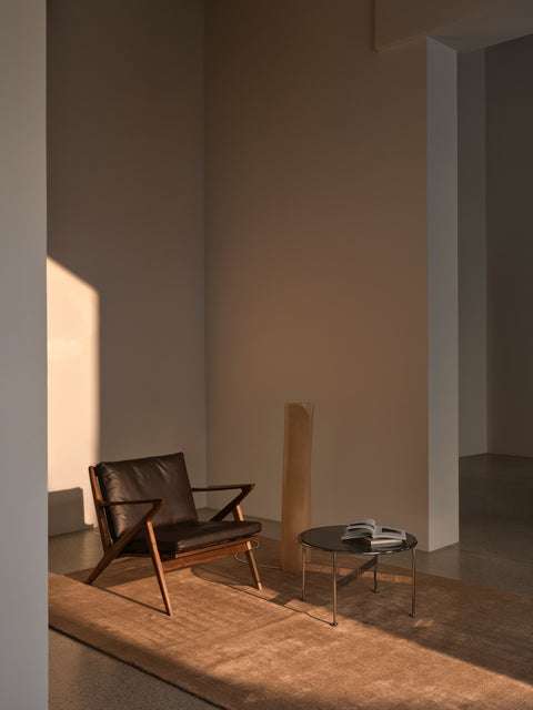 DK3 Baia Coffee and Side Table in Chrome, medium round glass table beside a leather lounge chair with a wooden Z-shaped frame