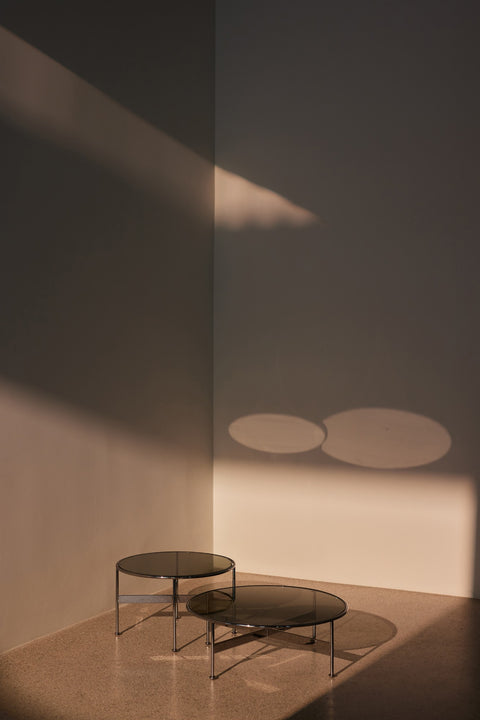 DK3 Baia Coffee and Side Table in Chrome, medium and large round glass tables in a sunlit corner on a terrazzo floor