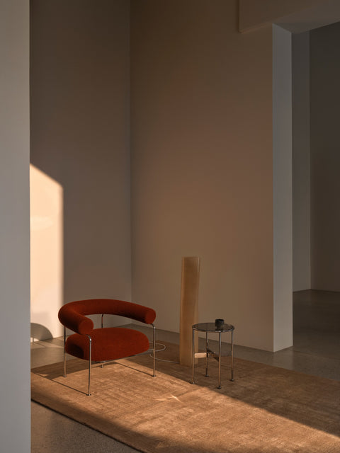 DK3 Baia Coffee and Side Table in Chrome, small round glass side table beside a red upholstered chair on a sand-coloured rug