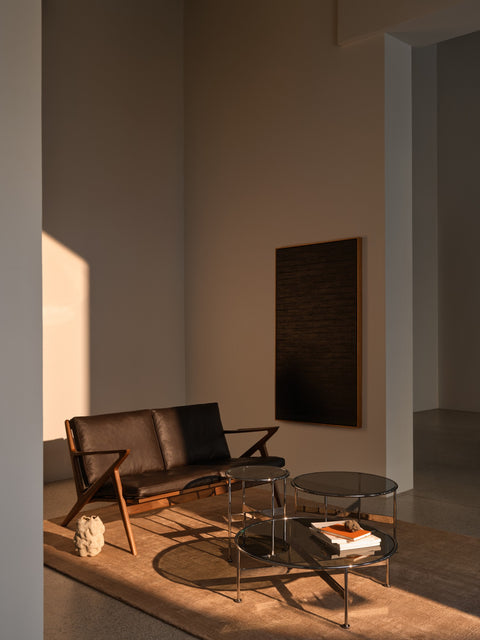 DK3 Baia Coffee and Side Table in Chrome, three round glass tables in all three sizes grouped in front of a leather two-seat sofa