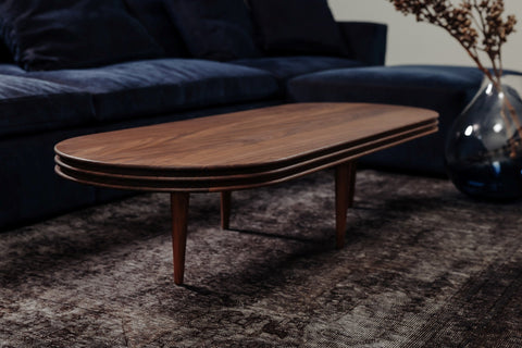 DK3 Groove Coffee Table Oval in smoked oak on a rug in front of a dark blue sofa