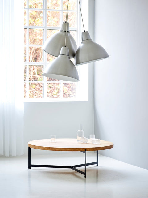 DK3 Plateau Coffee and Side Table in oiled oak below three pendant lamps in a white room
