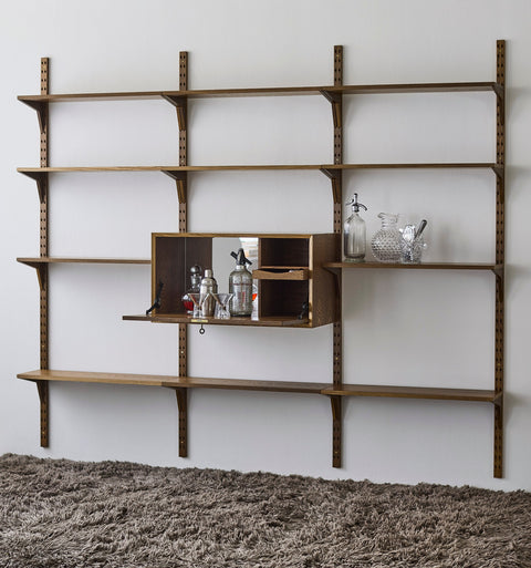 DK3 System Cado drop-front cabinet with mirror and shelf in smoked oak, open as a bar on a smoked oak shelving wall