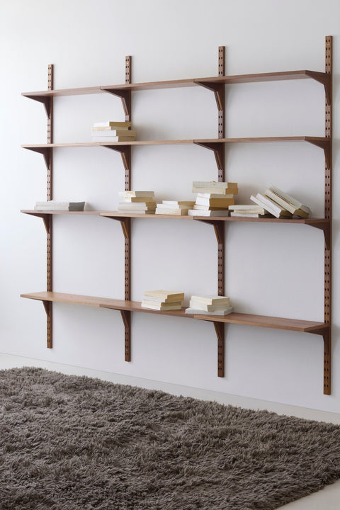 DK3 System Cado wall rails in smoked oak with four rows of shelves above a shaggy rug