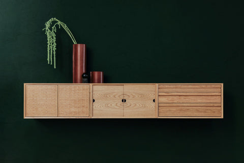 DK3 System Cado Sideboard in oak, wall mounted with sliding and woven fronts against a dark green wall