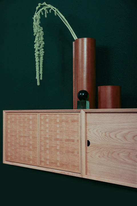 DK3 System Cado Sideboard in oak, woven front cabinet shown open against a dark green wall