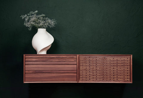DK3 System Cado Sideboard in walnut, wall mounted with woven fronts against a dark green wall
